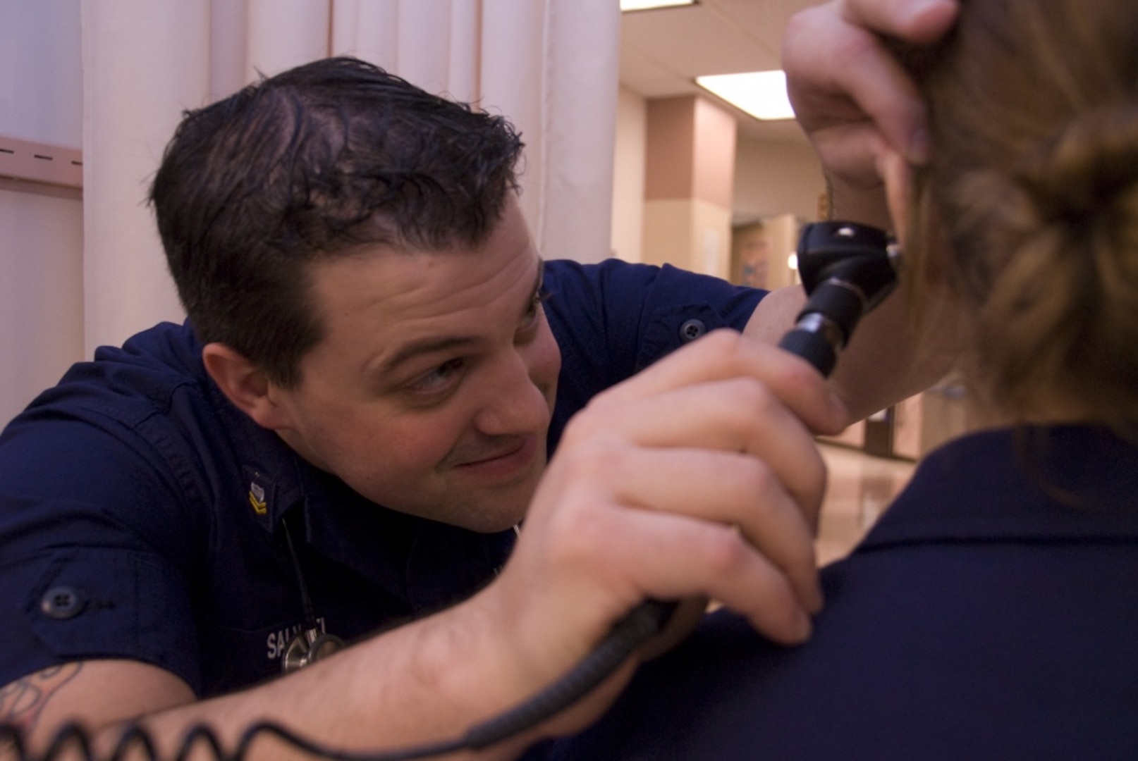 Petty Officer 2nd Class Joseph Salvati, a health services technician with Health, Safety and Work-Life Field Office's Rockmore King Clinic, checks for an ear infection Oct. 8 at the clinic.