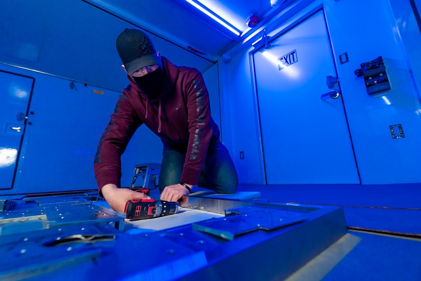 Photo of Sheet Metal Mechanic Thomas Hodorovich installs hardware in a BDOC shelter.