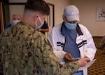 A U.S. Navy retiree, receives a COVID-19 immunization card