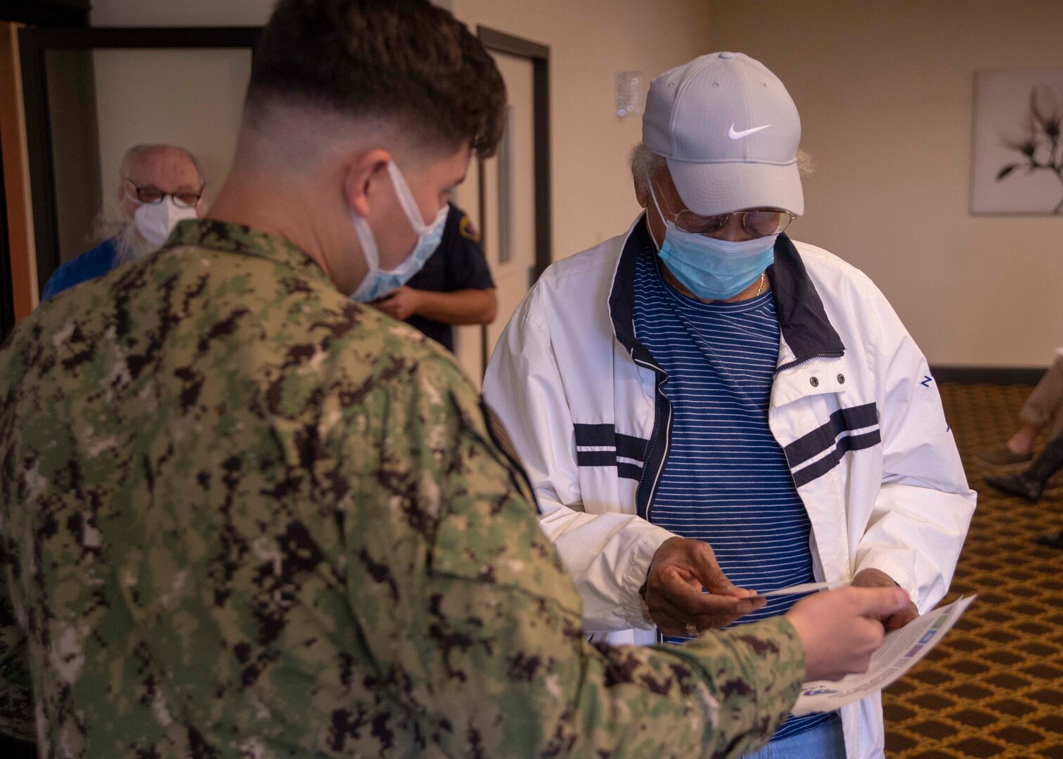 A U.S. Navy retiree, receives a COVID-19 immunization card