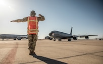 Airman uses hand signals to guide airplane.