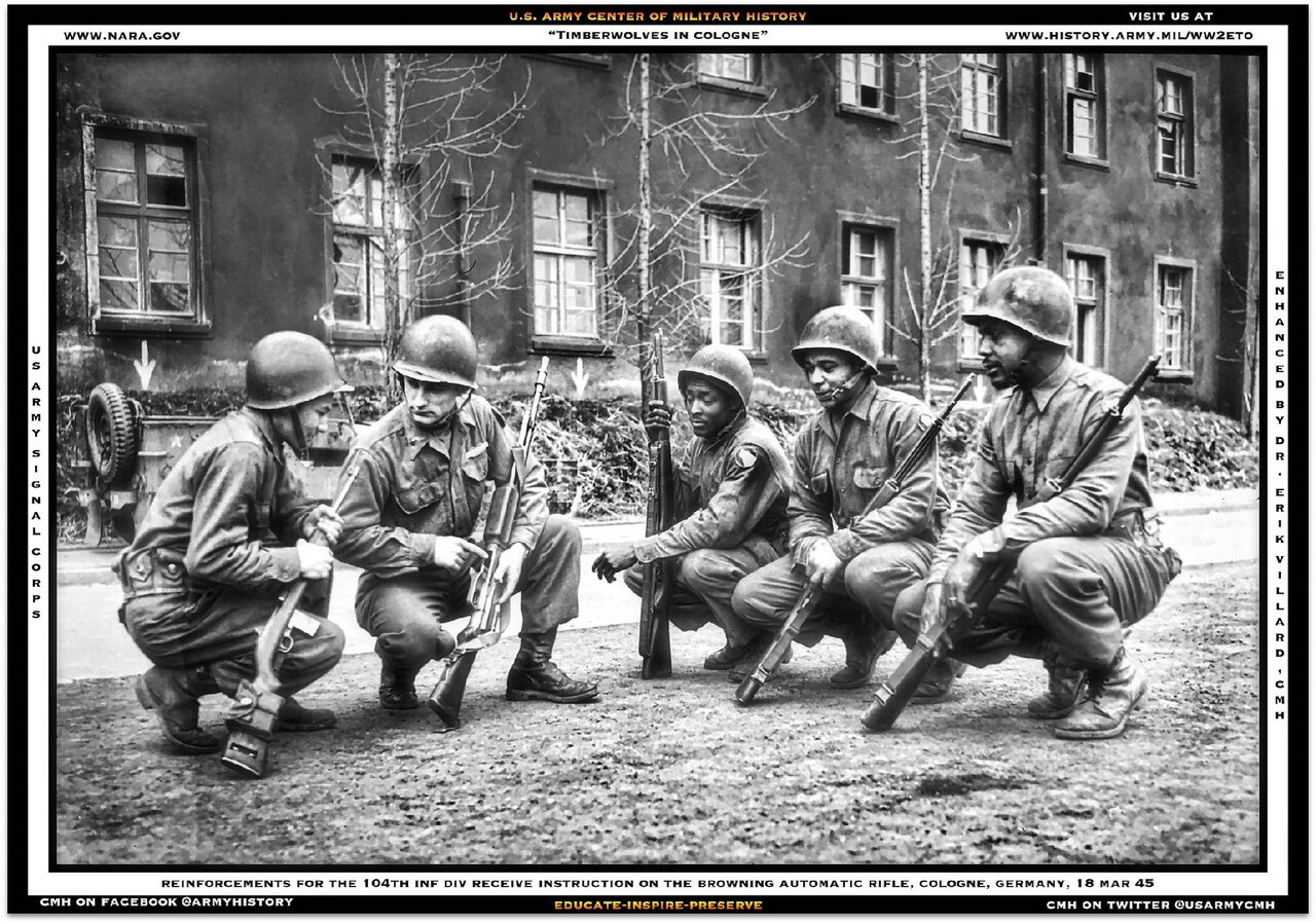 Five soldiers in helmets squat down in a street to look at one soldier's gun.