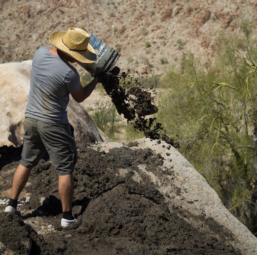 A U.S. Marine volunteer with the Single Marine Program (SMP) throws built-up silt from a Bighorn Sheep watering hole at the Betty Lee Tank in Yuma, Ariz., Mar 20, 2021.