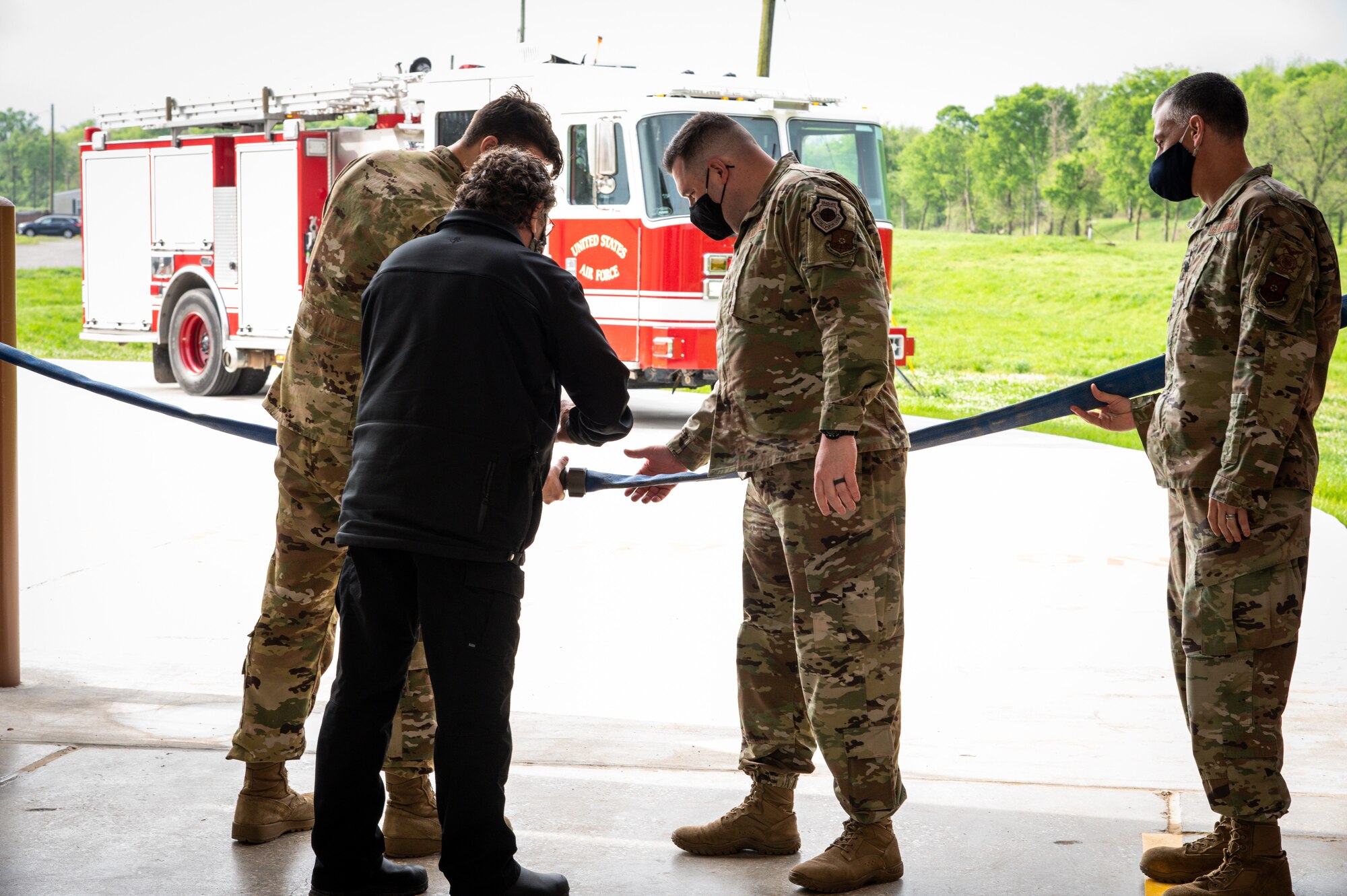 Col. Mark Dmytryszyn, 2nd Bomb Wing commander, middle, Lt. Col. Christopher Carnduff, 2nd Civil Engineer Squadron commander, right, Timothy Sprague, fire chief, middle left, and Amn. Maxwell Palmer, 2nd Civil Engineer Squadron firefighter, left, detach a connected fire hose symbolizing the cutting of a ribbon for Fire Station Two at Barksdale Air Force Base, Louisiana, April 7, 2021.
