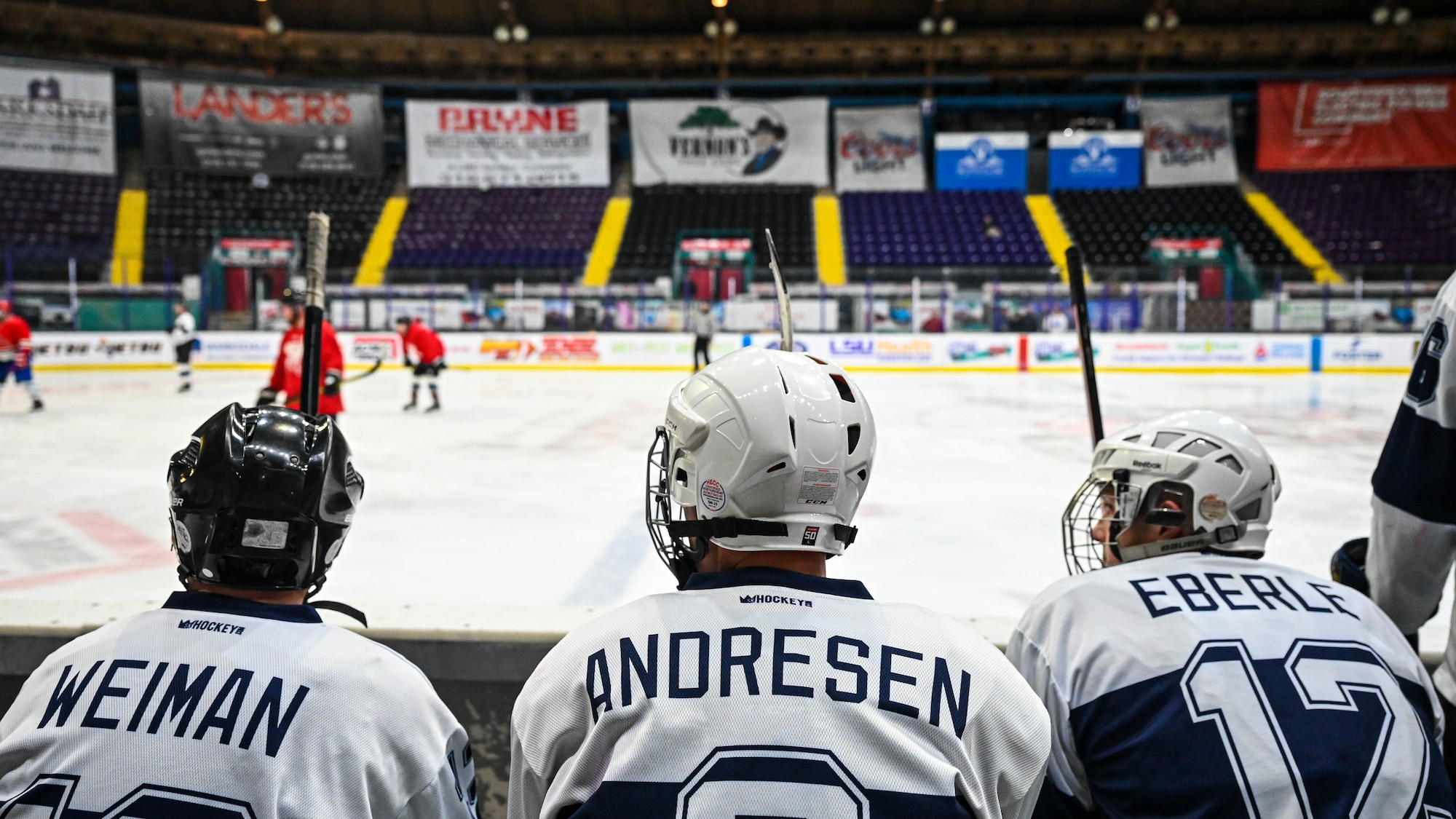 Master Sgt. Jonathan Weiman, Lt. Col. Scott Andresen, and Lt. Col. Scott Eberle, Barksdale Bombers hockey team members, watch as their team competes at Hirsch Memorial Coliseum in Shreveport, Louisiana, March 31, 2021.