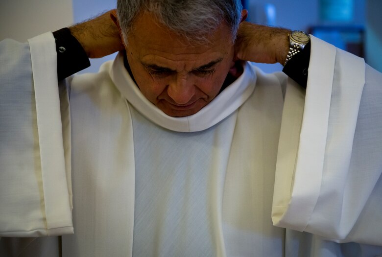 Retired Chaplain (Lt. Col.) Robert Bruno adjusts his white alb before entering the dormitory chapel for morning prayer. The alb is the common vestment for all ministers at Mass.  (U.S. Air Force photo/Staff Sgt. Andrew Lee)