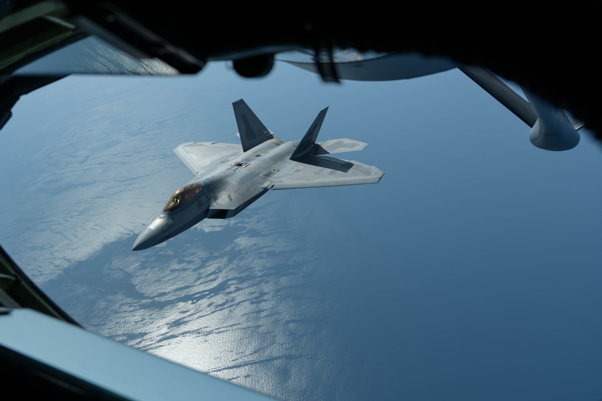 A U.S. Air Force F-22 Raptor from the 199th Fighter Squadron assigned to Joint Base Pearl Harbor-Hickam, Hawaii, flies alongside a KC-135 Stratotanker from the 909th Air Refueling Squadron from Kadena Air Base, Japan, after being refueled, April 1, 2021. The 199th Fighter Squadron deployed to Marine Corps Air Station Iwakuni, Japan, to conduct integrated training with Marine and Naval forces as part of U.S. Indo-Pacific Command’s dynamic force employment concept. (U.S. Air Force photo by Senior Airman Rebeckah Medeiros)