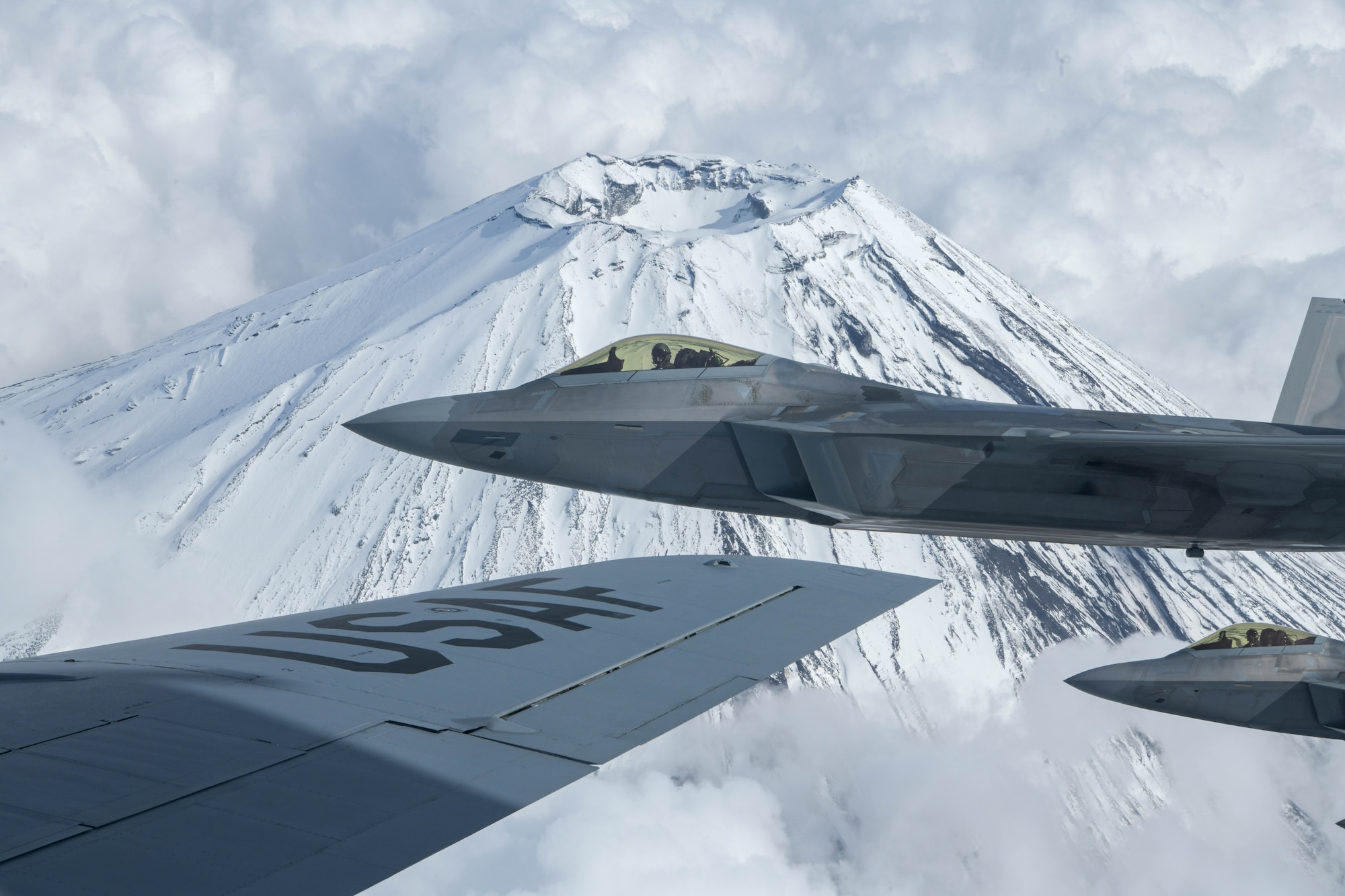 U.S. Air Force Raptors from the 199th Fighter Squadron fly alongside a U.S. Air Force KC-135 Stratotanker from the 909th Air Refueling Squadron during 5th generation fighter training near Mt. Fuji, Japan, April 1, 2021. The F-22 Raptors are currently operating out of Marine Corps Air Station Iwakuni, Japan, to support U.S. Indo-Pacific Command’s dynamic force employment concept. (U.S. Air Force photo by Senior Airman Rebeckah Medeiros)