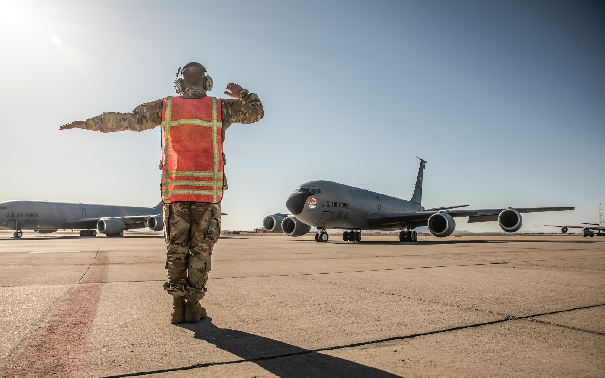 Airman uses hand signals to guide airplane.