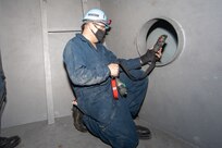 SurgeMain (Surge Maintenance) Sailors checking the air for gas in the mock up confined space, another component of their required training to work with the Navy Competent Persons (NCP).