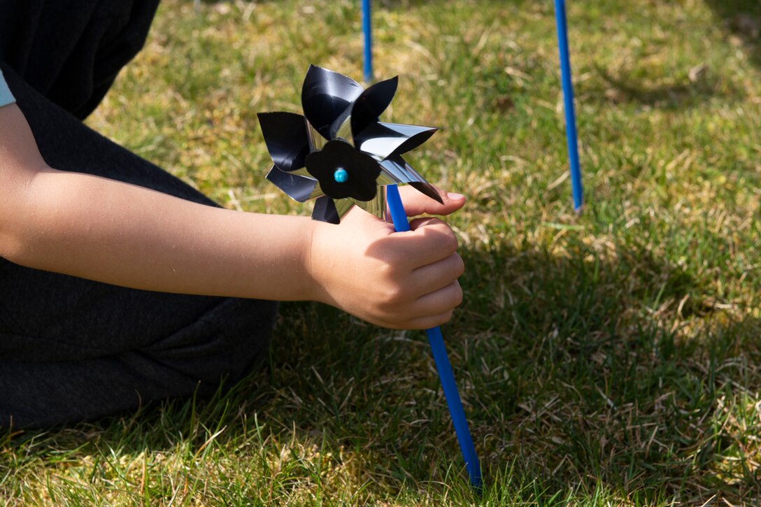 A child plants a pinwheel at the Child Development Center on Spangdahlem Air Base, Germany, April 1, 2021. The pinwheel is a national symbol for Child Abuse Prevention Month, and each one represents a victim of child abuse and neglect. (U.S. Air Force photo by Senior Airman Melody W. Howley)