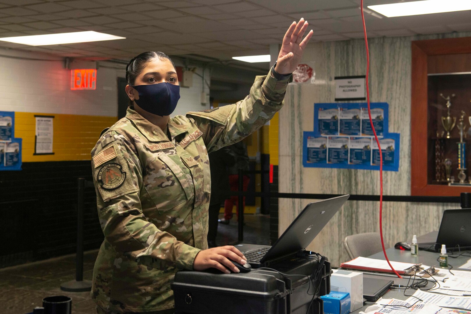 U.S. Air Force Staff Sgt. Madeline Negron-Lisboa, from Norwich, Connecticut, and a general purpose Airman assigned to the 335th Expeditionary Medical Operations Squadron, waves to invite a community member to check-in at the state-led, federally-supported Medgar Evers College Community Vaccination Center in Brooklyn, New York, on March 22, 2021.
