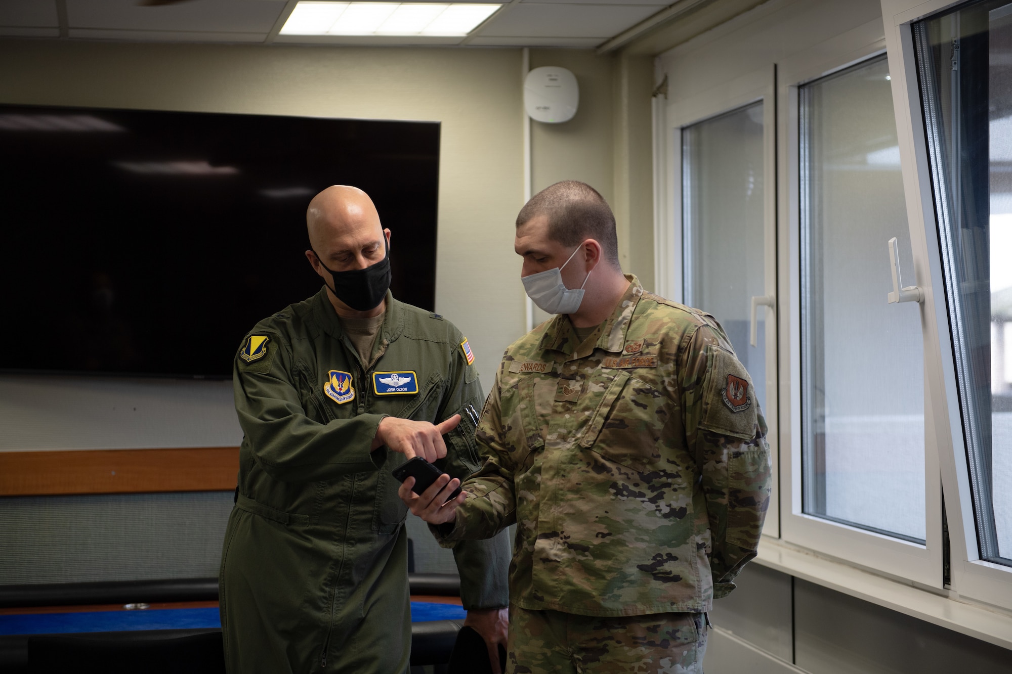 Man shows other man messenger program on phone.