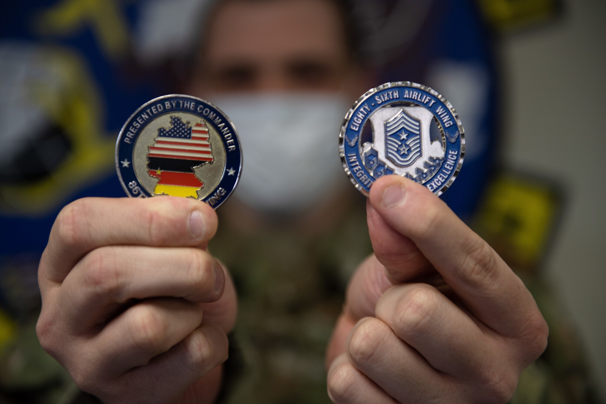 Man holds up two challenge coins.