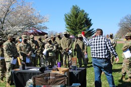 man hold cup and group of soldiers watch