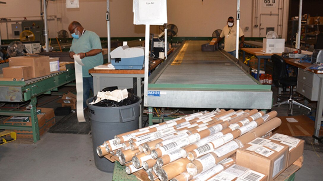 Edward Seaborne, Jr. and Carlton Drummond, both materials handlers from Defense Logistics Agency Distribution, prepare packages to mail mapping products to customers