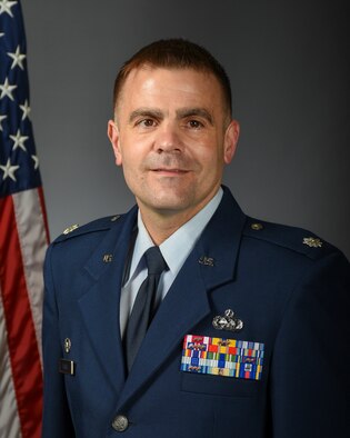 Lt. Col. David Black with American flag behind his right shoulder and a solid gray background