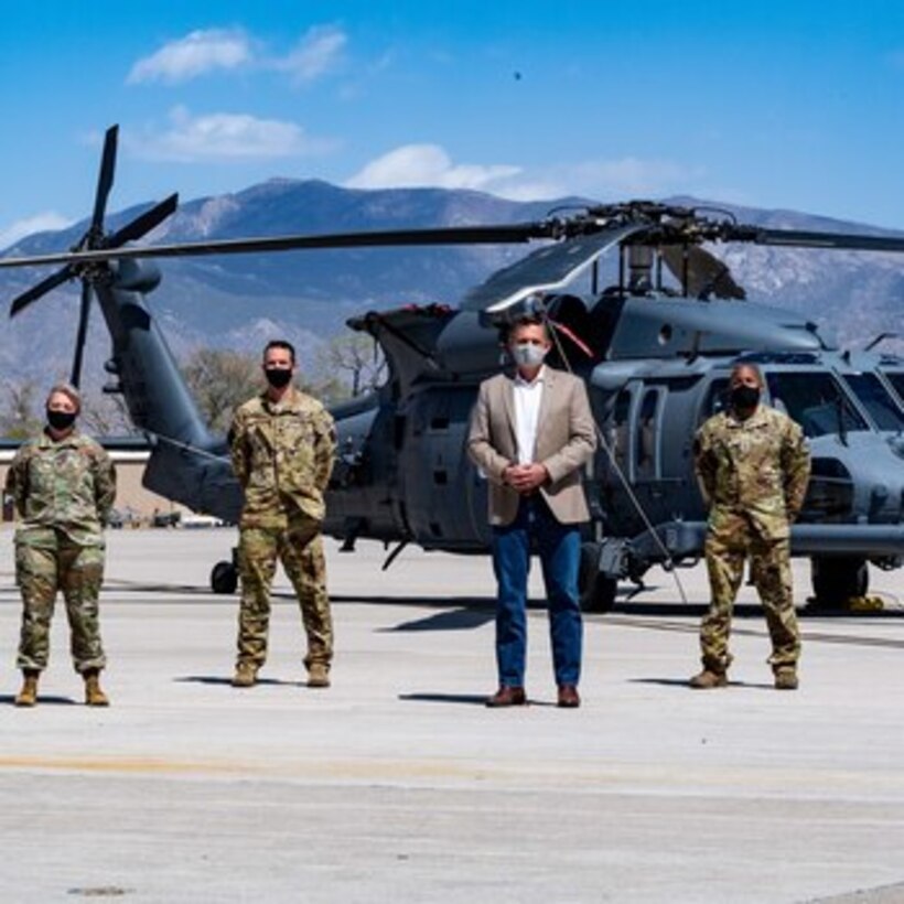 Four people pose for photo in front of U.S. Air Force HH-60W helicopter at Kirtland AFB, N.M.