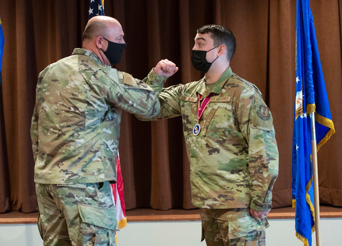 Col. Patrick Miller, 88th Air Base Wing commander, elbow-bumps Staff Sgt. Marc Lejeune during the Airman Leadership School Class 21-C graduation ceremony inside the base club at Wright-Patterson Air Force Base, Ohio, March 25, 2021. Miller recognized and presented a coin to Lejeune at the graduation for initiating basic first aid to a neighbor March 23.