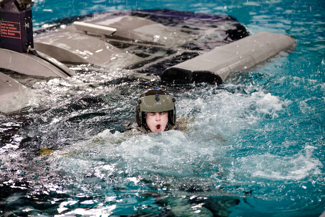 An Army National Guard ROTC cadet takes a big breath while in a pool next to military equipment.
