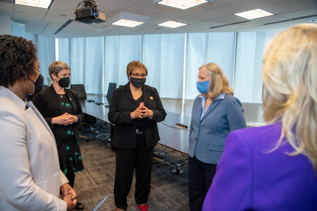 Five women stand in a semicircle visit with each other at  a military call center.