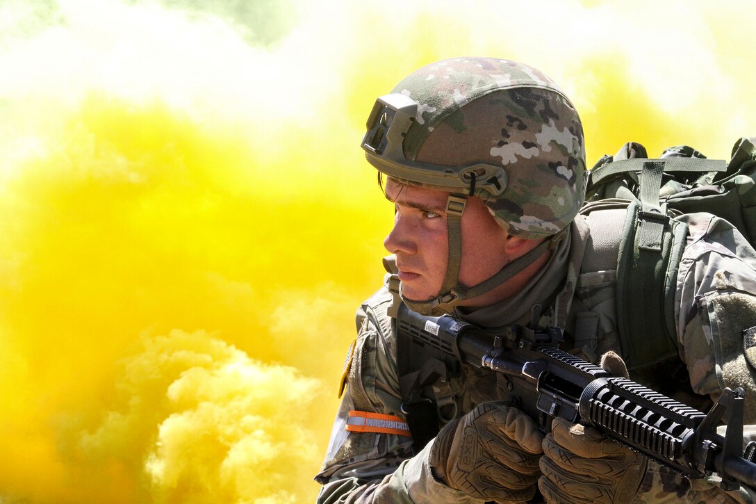 A soldier wielding a weapon looks in front of him as yellow smoke billows behind him.