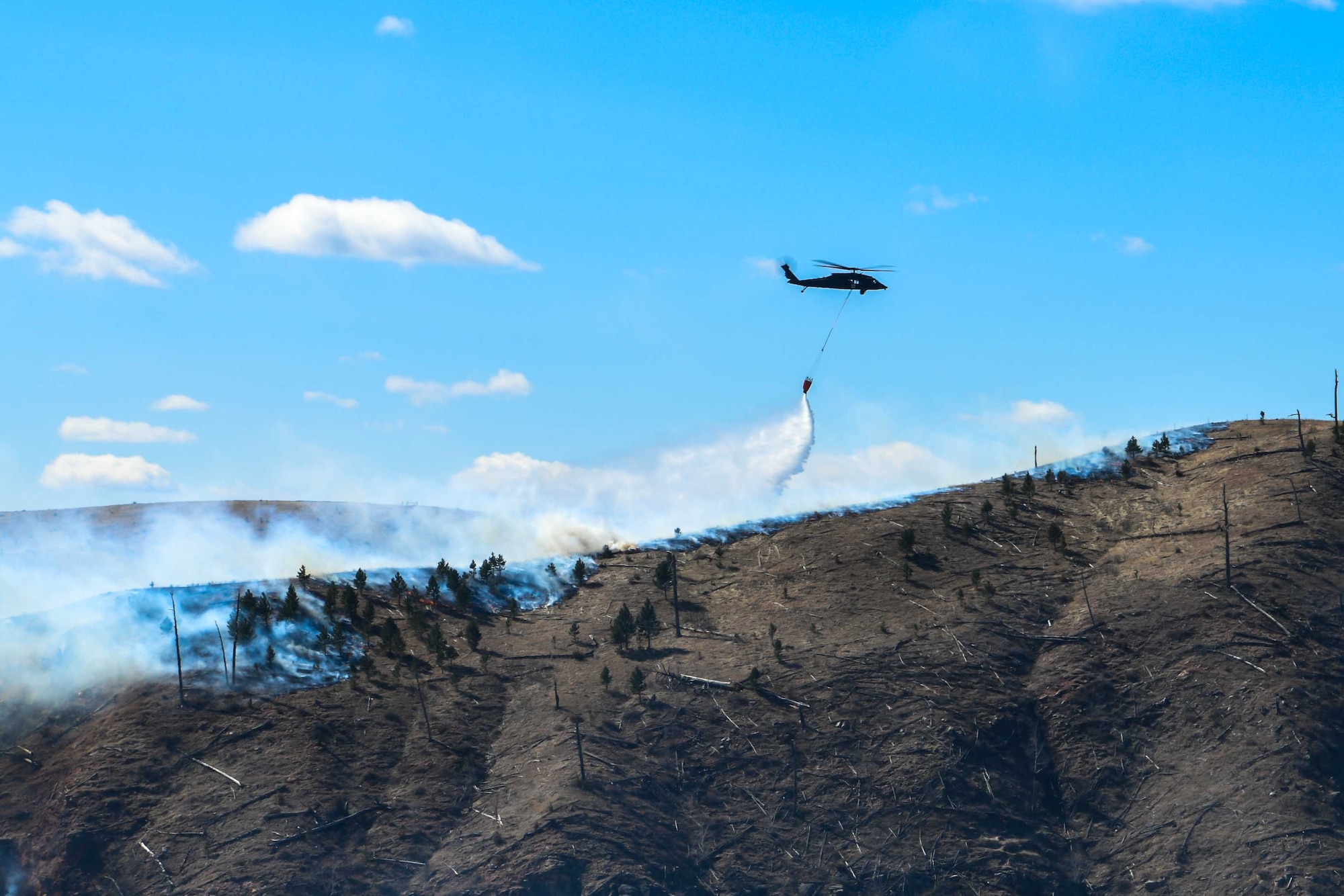Hawk helicopter drops water from its bucket to help fight Schroeder’s Fire in Rapid City, S.D., March 30, 2021. The fire started March 29 in the Black Hills four miles west of Rapid City.