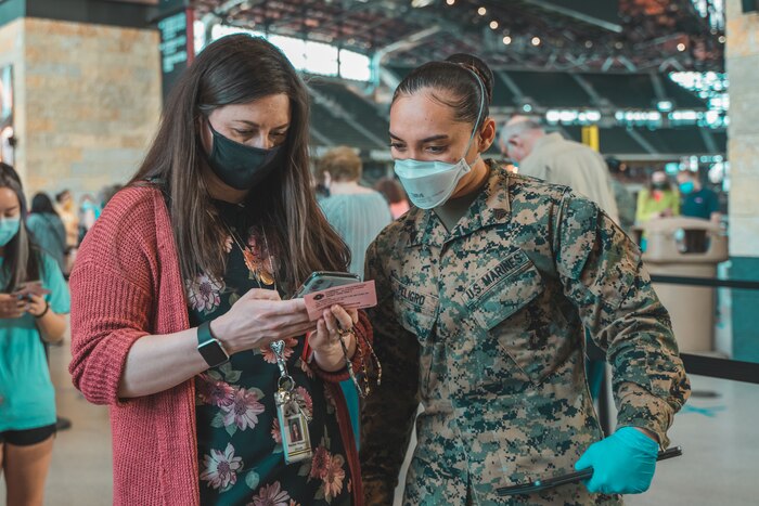 A soldier speaks with a woman who is looking at her phone.