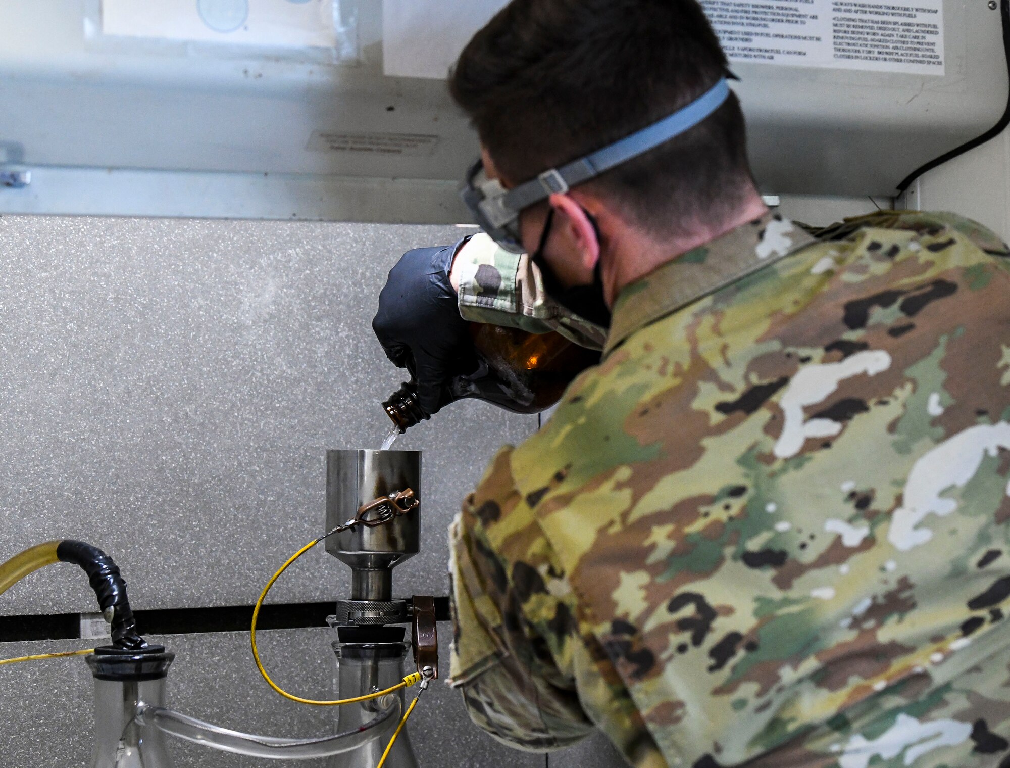 Staff Sgt. Brian Elrod, 436th Logistics Readiness Squadron fuels laboratory noncommissioned officer in charge, pours fuel into a bottle-method funnel during the fuel testing process at Dover Air Force Base, Delaware, Jan. 12, 2021. The bottle-method test measures levels of water, additives, sediment and particulates in fuel to ensure all aircraft receive the cleanest fuel possible. (U.S. Air Force photo by Airman 1st Class Stephani Barge)