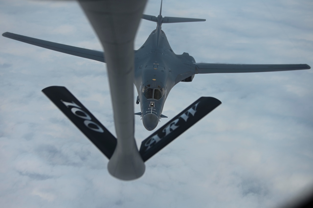 An aircraft is refueled by another aircraft in mid-air.
