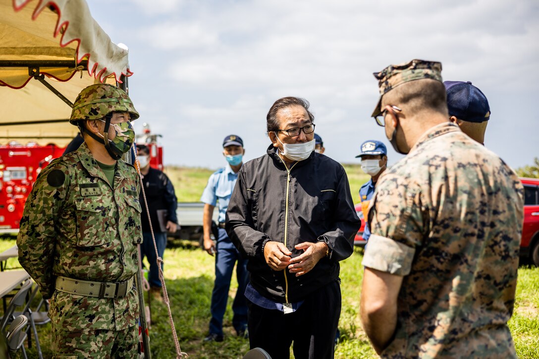 Japan Ground Self-Defense Force (JGSDF) Maj. Gen. Sato Makoto, left, the 15th Brigade commanding general, Hideyuki Shimabukuro, middle, the Ie Village office mayor and Marine Corps Installations Pacific (MCIPAC) representatives, right, discuss about the unexploded ordnance (UXO) disposal operations on Ie Shima Training Facility (ISTF), Okinawa, Japan, April 6, 2021. Over the past five years, ordnance has been collected on Iejima and stored away. At the request of the Ie Village office mayor, the JGSDF and MCIPAC explosive ordnance disposal technicians conducted combined UXO disposal operations to destroy the collected ordnance. ISTF is the only active demolition range aboard Iejima where the operation can be conducted. (U.S. Marine Corps photo by Cpl. Terry Wong)