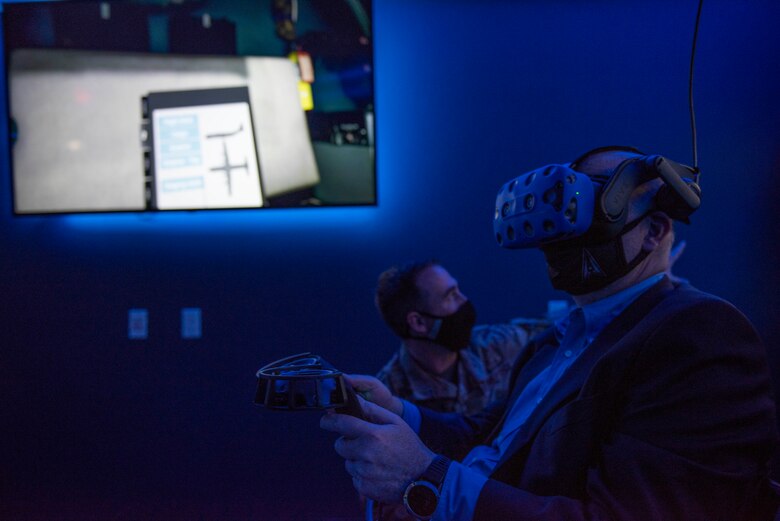 Staff Sgt. Christopher Clinton, 317th Maintenance Group Virtual Reality NCO in charge, directs Acting Secretary of the Air Force John Roth during a C-130J Super Hercules maintenance virtual reality presentation at Dyess Air Force Base, Texas, April 6, 2021. Clinton briefed Roth on the 317th MXG VR lab capabilities and advantages. Training on VR simultaneously provides Airmen with an individualized, hands-on training experience. (U.S. Air Force photo by Airman 1st Class Colin Hollowell)