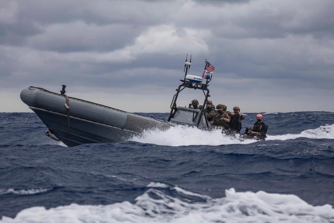 Sailors and Coast Guardsmen travel on a rubber boat in choppy seas with dark clouds overhead.