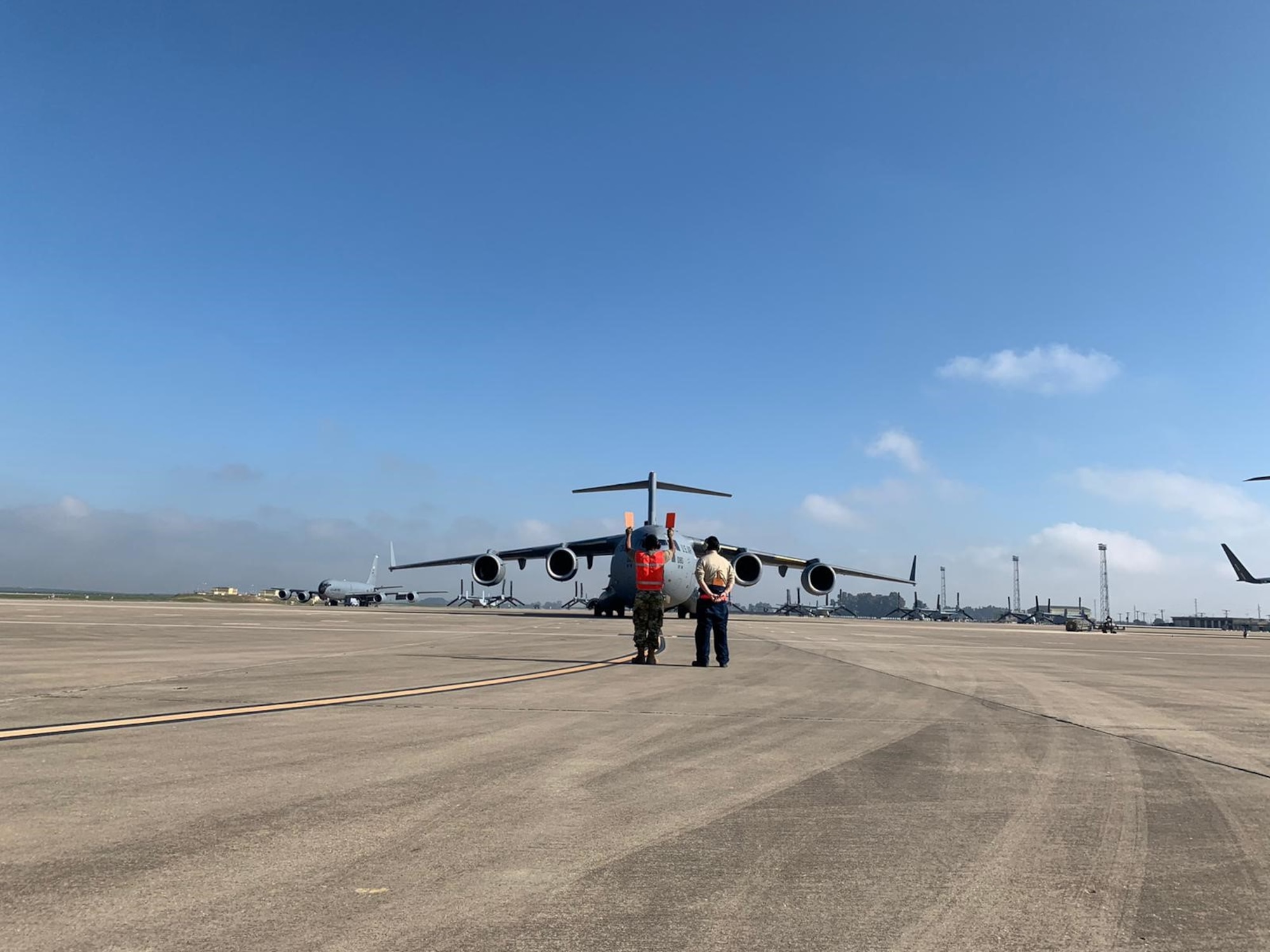 725th Air Mobility Squadron Guidance and Control Maintainer, Staff Sgt. Joseph Cho, teaches 721st Aerial Port Squadron Air Transportation Specialist, Senior Airman Juwan White, how to marshal a C-17 into position at Morón Air Base, April 6, 2021. Airmen of the 521st Air Mobility Operations Wing have been demonstrating the Wing’s Nodal Agile Combat Employment at the air base since the beginning of March. (U.S. Air Force photo by Staff Sgt. Michael Dodd)