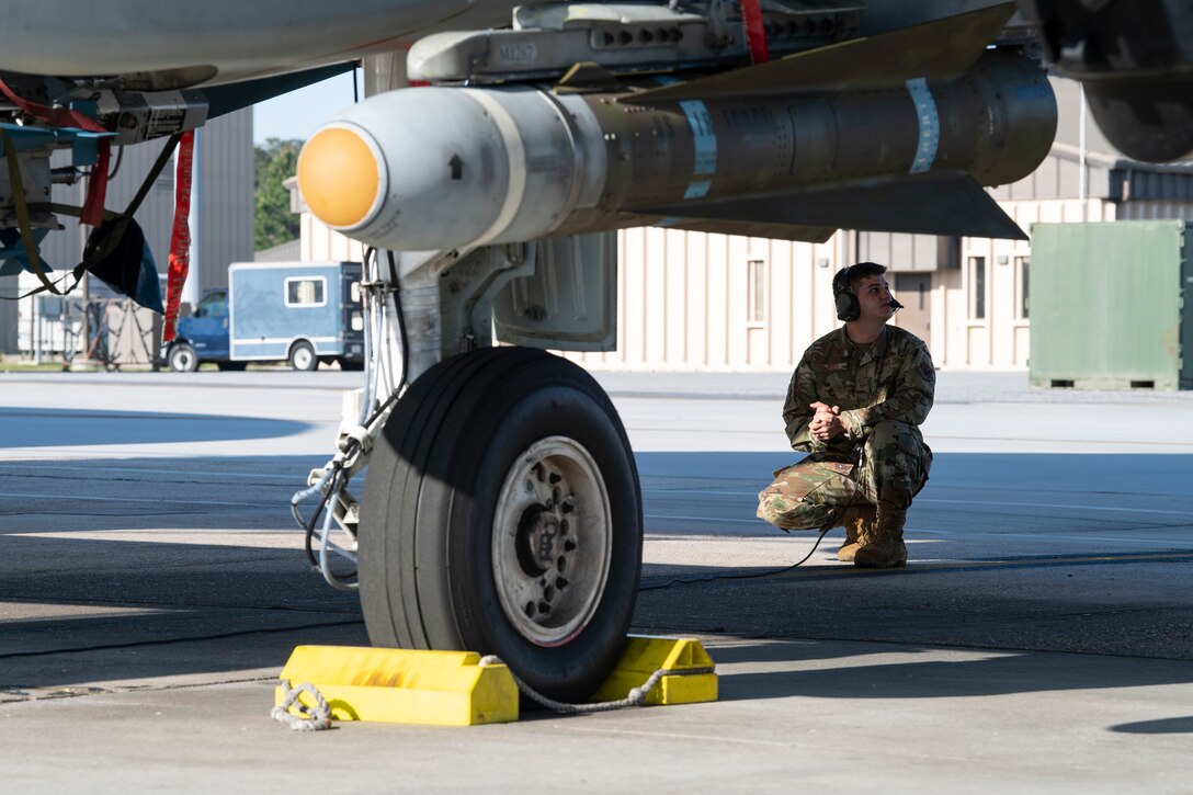 A photo of an Airman crouching underneath and A-10C Thunderbolt II.
