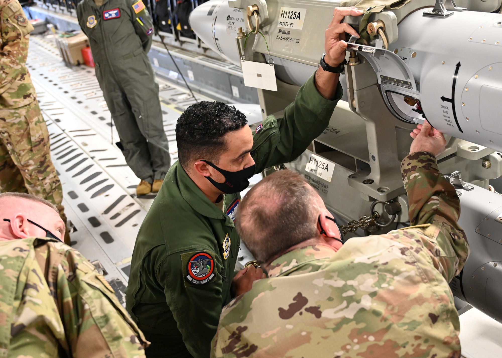 U.S. Air Force Staff Sgt. Gabriel Gonzales, 4th Airlift Squadron loadmaster, briefs Maj. Gen. Thad Bibb, 18th Air Force commander, and Chief Master Sgt. Chad Bickley, 18th AF command chief, on the Command Disablement System of a B-61 aboard a C-17 Globemaster III, at Joint Base Lewis-McChord, Washington, April 8, 2021. During the visit, Bibb and Bickley learned about the wing’s unique mobility mission and met with Airmen across the base, seeing firsthand who makes up Team McChord. (U.S. Air Force photo by Airman 1st Class Callie Norton)