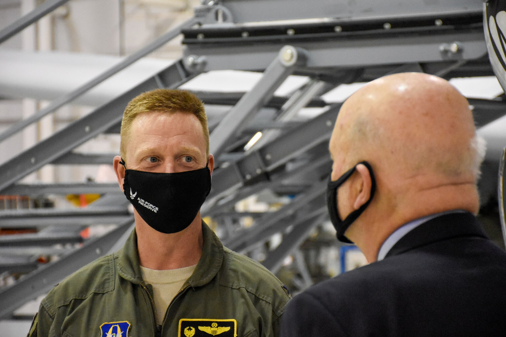 Acting Secretary of the Air Force John Roth departs the 5-Bay hangar with Colonel Jeffrey Schreiner in front of a large American flag.
