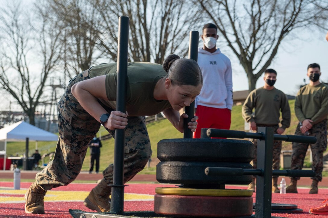A Marine pushes a weighted sled push.