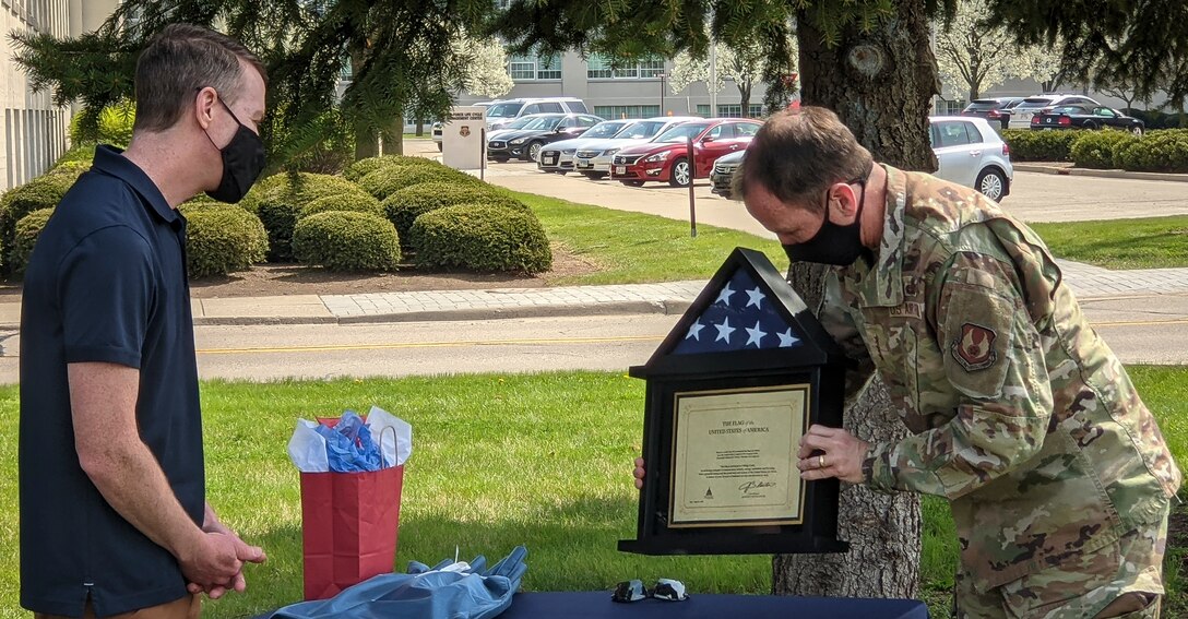 The Air Force Life Cycle Management Center commander, Lt. Gen. Shaun Morris, presents an American flag to Chief Master Sgt. Troie Croft after congratulating Croft for his 28 years of service to the Air Force during a retirement luncheon.