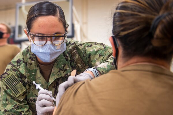 A hospital corpsman administers the COVID-19 vaccine to a Sailor onboard Naval Air Station Oceana.