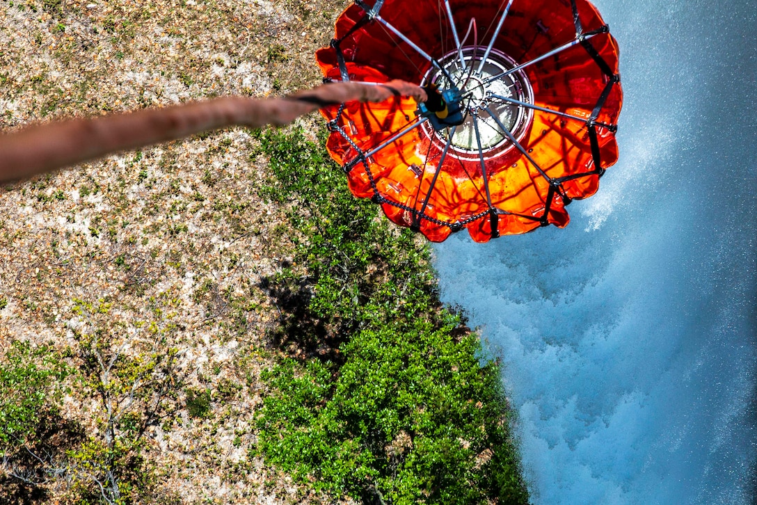 A water bucket hangs from an aircraft.