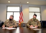 Col. Terry McClain, 433rd Airlift Wing commander, and Col. Rick Erredge, 960th Cyberspace Wing commander, sign copies of their respective versions of the 433rd AW and 960th CW Memorandum of Understanding, April 6, 2021, at Joint Base San Antonio-Lackland, Texas. (U.S. Air Force photo by Samantha Mathison)