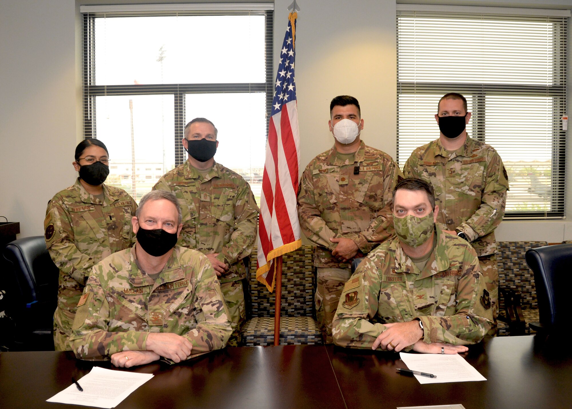 Col. Terry McClain, 433rd Airlift Wing commander, and Col. Rick Erredge, 960th Cyberspace Wing commander, pause for a photograph with the team who collaborated on the Memorandum of Understanding between the two wings, April 6, 2021, at Joint Base San Antonio-Lackland, Texas. Behind them, from left to right; 1st Lt. Rosario Genuardi, 433rd Logistics Readiness Squadron senior logistics manager, Chief Master Sgt. Byron Frost, 433rd AW acting command chief, Maj. Juan Perez, 960th Operations Support Flight director of operations, and Chief Master Sgt. Christopher Howard, 960th CW, acting command chief. (U.S. Air Force photo by Samantha Mathison)