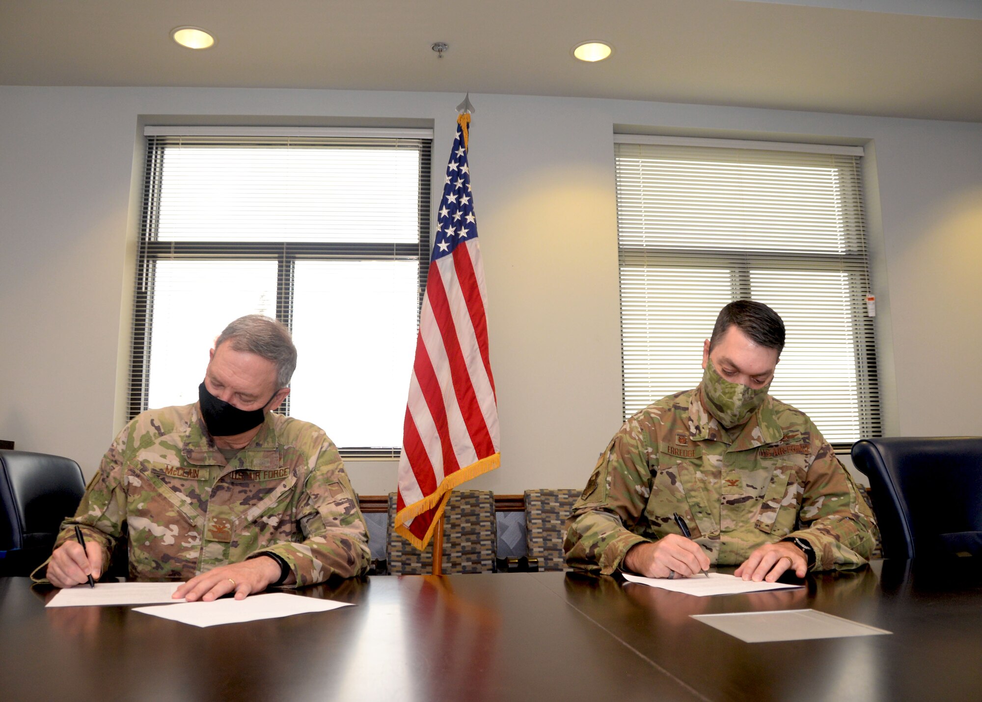 Col. Terry McClain, 433rd Airlift Wing commander, and Col. Rick Erredge, 960th Cyberspace Wing commander, sign copies of their respective versions of the 433rd AW and 960th CW Memorandum of Understanding, April 6, 2021, at Joint Base San Antonio-Lackland, Texas. (U.S. Air Force photo by Samantha Mathison)