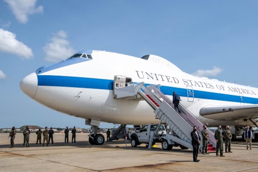 A man goes up some stairs to board a military aircraft.