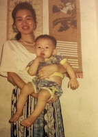Army Reserve Spc. Feiyu He, deployed to Camp Arifjan, Kuwait, with the Lancaster, Pennsylvania-based 1185th Deployment and Distribution Support Battalion, is held by his mother in this undated photo. The Chinese-born Soldier works as a yard specialist at Kuwait's Shuaiba Port. He has applied for U.S. citizenship with the support of 1st Theater Sustainment Command's operational command post at the camp. (Photo courtesy of Feiyu He)