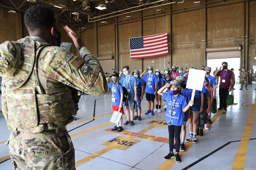 Reserve Citizen Airmen 2nd Lt. Solomon Waddles, 944th Maintenance Group, teaches little Airmen how to salute during Operation Reserve Kids at Luke Air Force Base, Arizona, April 10, 2021. The children got a behind-the-scenes look at an F-16 Fighting Falcon and F-35 Lightning, met some retired working dogs, ate field rations, and shot at targets with paintball guns.