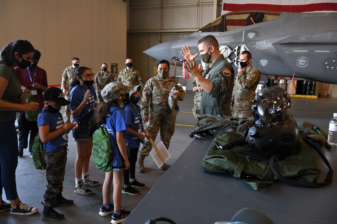 Reserve Citizen Airmen Maj. Jordan Levine, 944th Operations Group instructor pilot, explain how pressure effects the body while flying the F-35 Lightning during Operation Reserve Kids at Luke Air Force Base, Arizona, April 10, 2021. The children were given the opportunity to hold the helmet, see the G-suit, and walk around the air frame.
