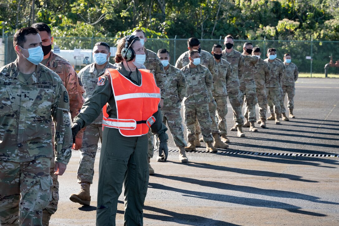 Master Sgt. Caroline Sussman, 201st Air Operations Group loadmaster, guides Hawaii National Guard Airmen and Soldiers toward a C-17 Globemaster III on Jan. 5, 2021, at Hilo, Hawaii.