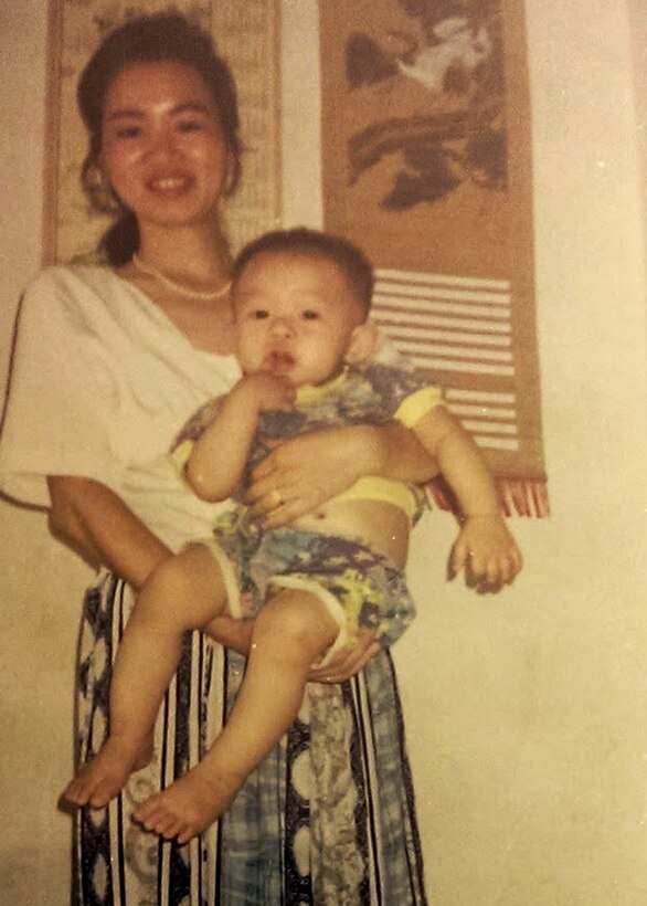 Army Reserve Spc. Feiyu He, deployed to Camp Arifjan, Kuwait, with the Lancaster, Pennsylvania-based 1185th Deployment and Distribution Support Battalion, is held by his mother in this undated photo. The Chinese-born Soldier works as a yard specialist at Kuwait's Shuaiba Port. He has applied for U.S. citizenship with the support of 1st Theater Sustainment Command's operational command post at the camp. (Photo courtesy of Feiyu He)